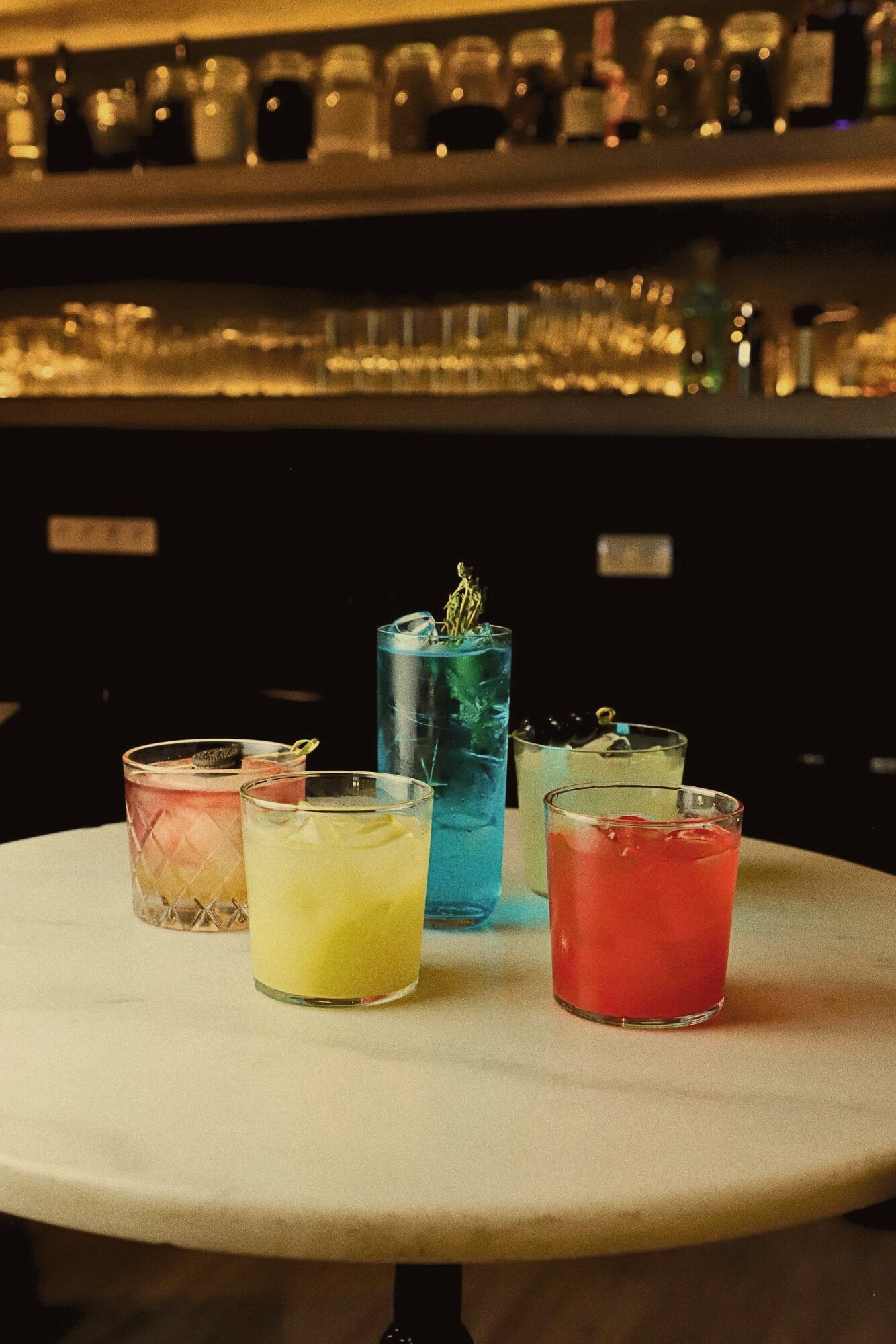 Cocktails of different colours lined up on the bar at Stillroom